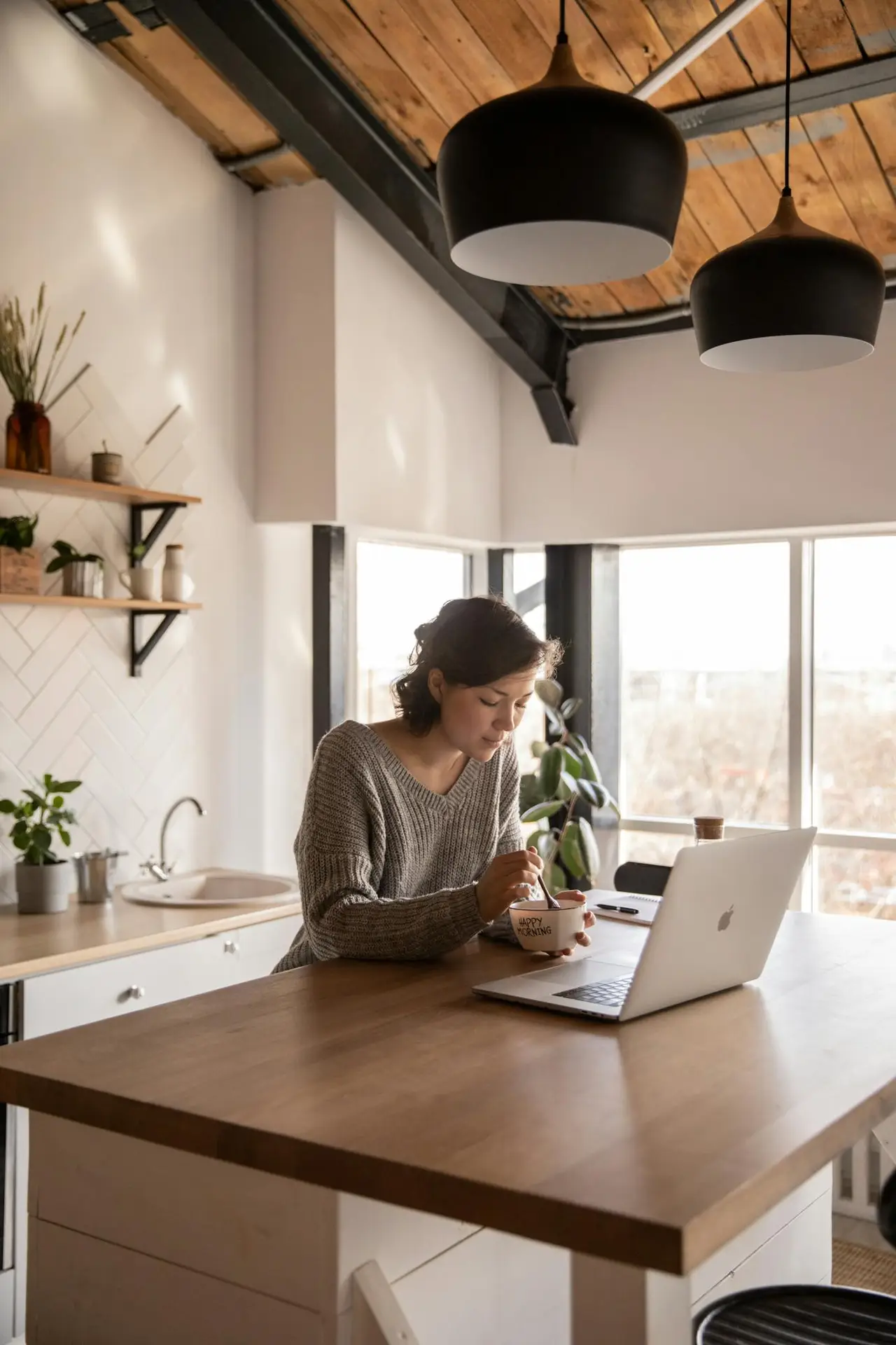 Young woman using laptop while eating breakfast